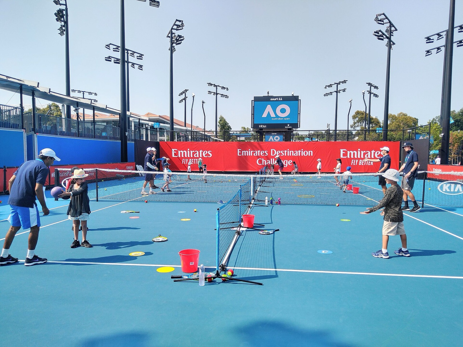Children and adult leaders on small tennis courts during a beginner racket-and-ball activity