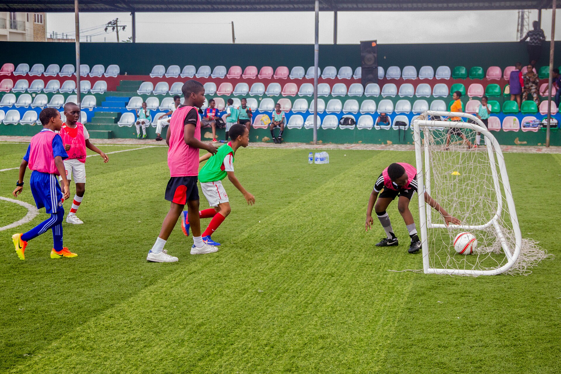 Children gathering around a small football goal after the ball crosses the line