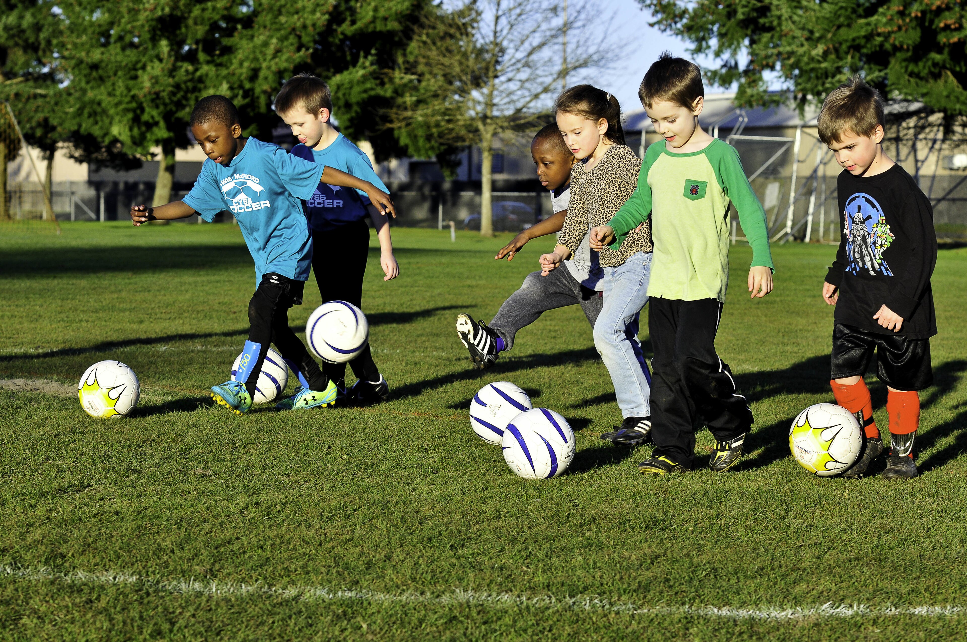 Children working with footballs on grass during a supervised youth practice
