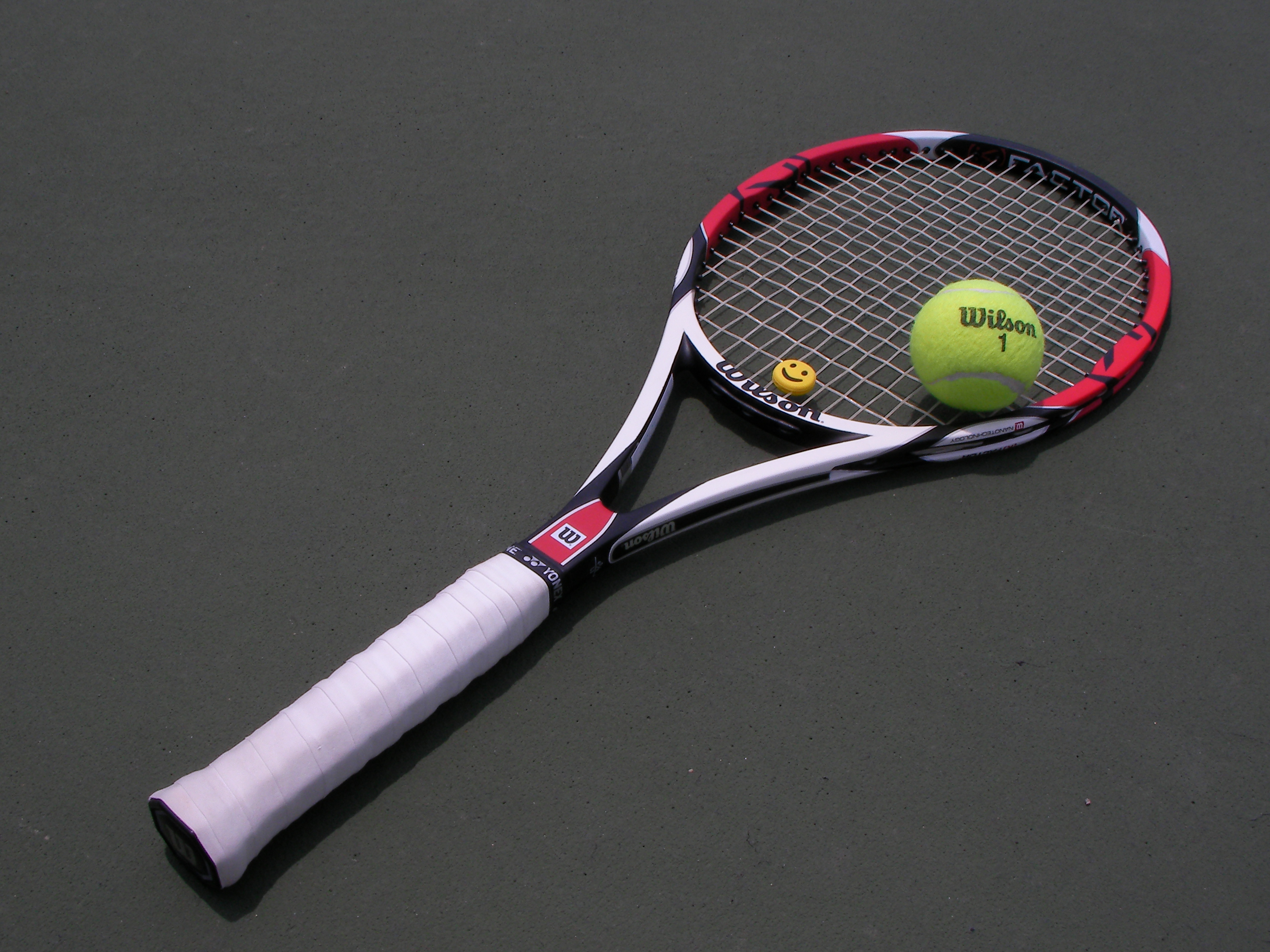 Tennis racket and ball placed on a clear hard surface before a home practice