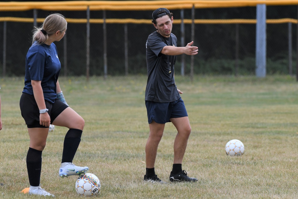 Young football player controlling a ball beside a coach